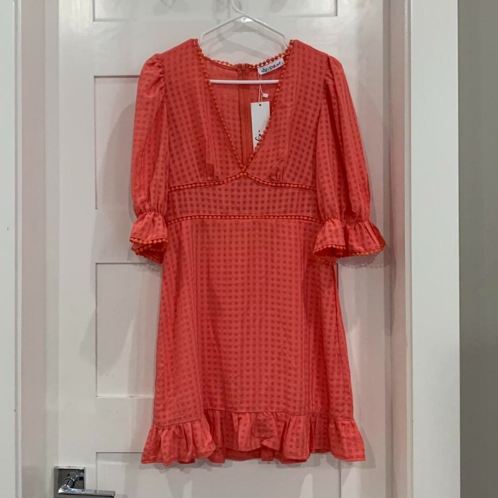 coral orange dress with ruffle detailing and V neckline